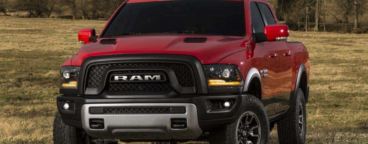 A red 2016 Ram 1500 is shown parked in a dry grassy field.