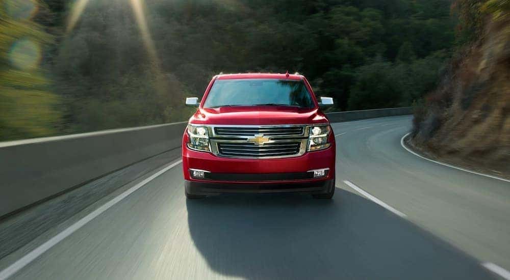 A red 2020 Chevy Tahoe is shown from the front driving on an open road after leaving a used SUV dealer.