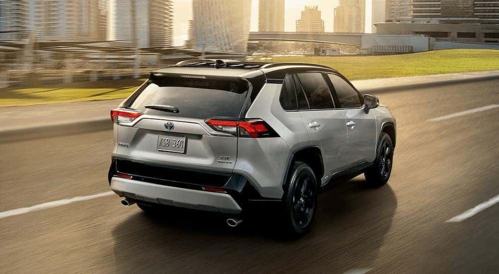 A grey 2020 Toyota RAV4 is shown from the rear driving on an open road.