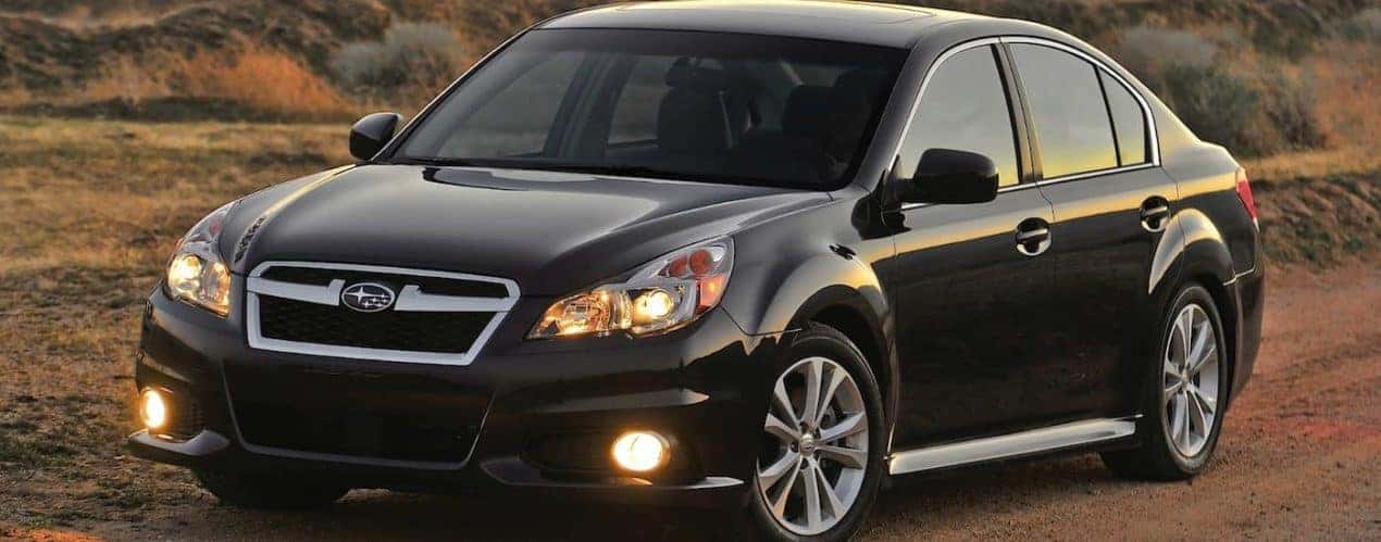 A black 2012 Subaru Legacy is shown parked on a dirt road.