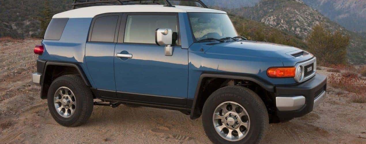 A blue 2012 Toyota FJ Cruiser is shown parked on a mountain trail.