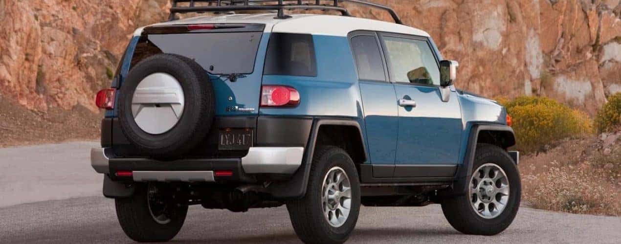 A blue 2014 Toyota Fj Cruiser is shown from a rear angled parked on the side of a road.