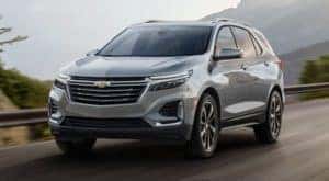A grey 2023 Chevy Equinox is shown from the front driving on an open road.