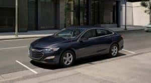 A blue 2023 Chevy Malibu is shown parked on a city street.