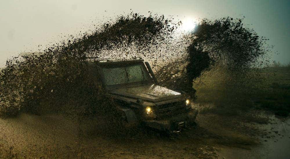 A vehicle is shown kicking up mud off-road.