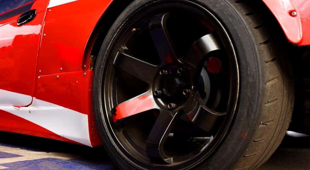 A close up shows a performance tire on a black rim.