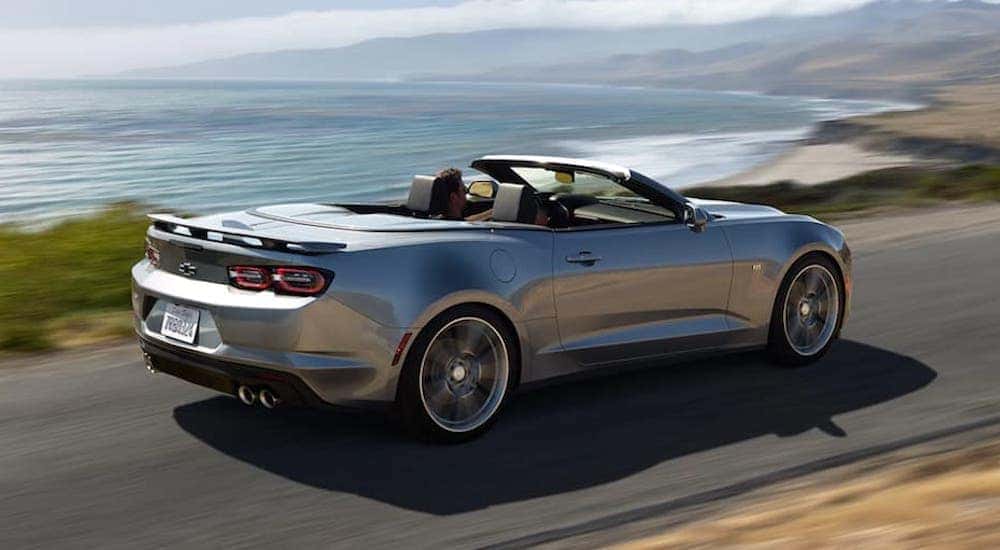 A Certified Pre-Owned silver 2021 Chevy Camaro is shown from the side on a coast.