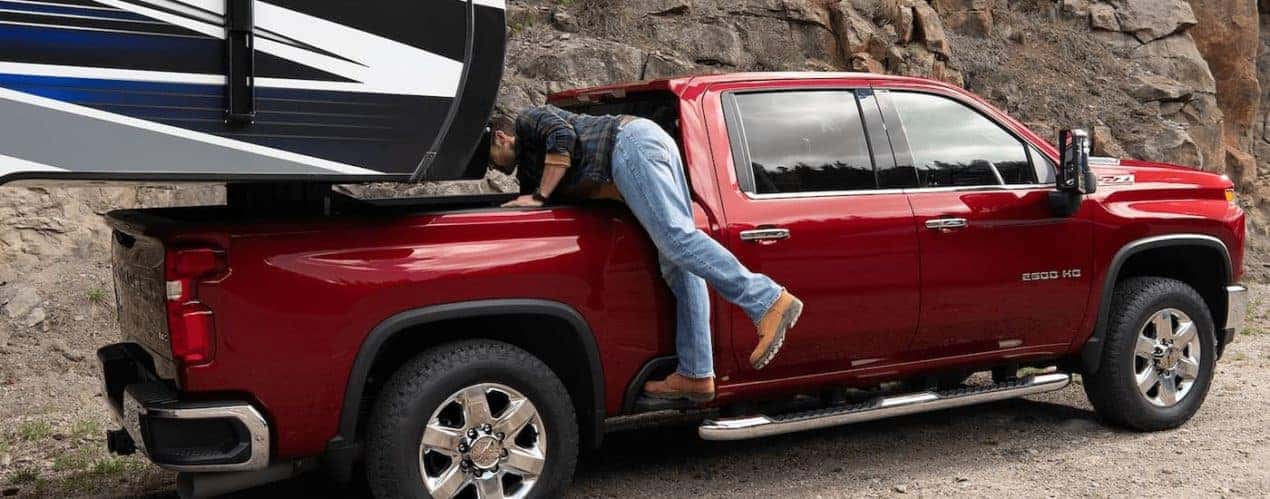 A man is shown getting supplies from the bed of a red 2023 Chevy Silverado 2500 HD Z71.