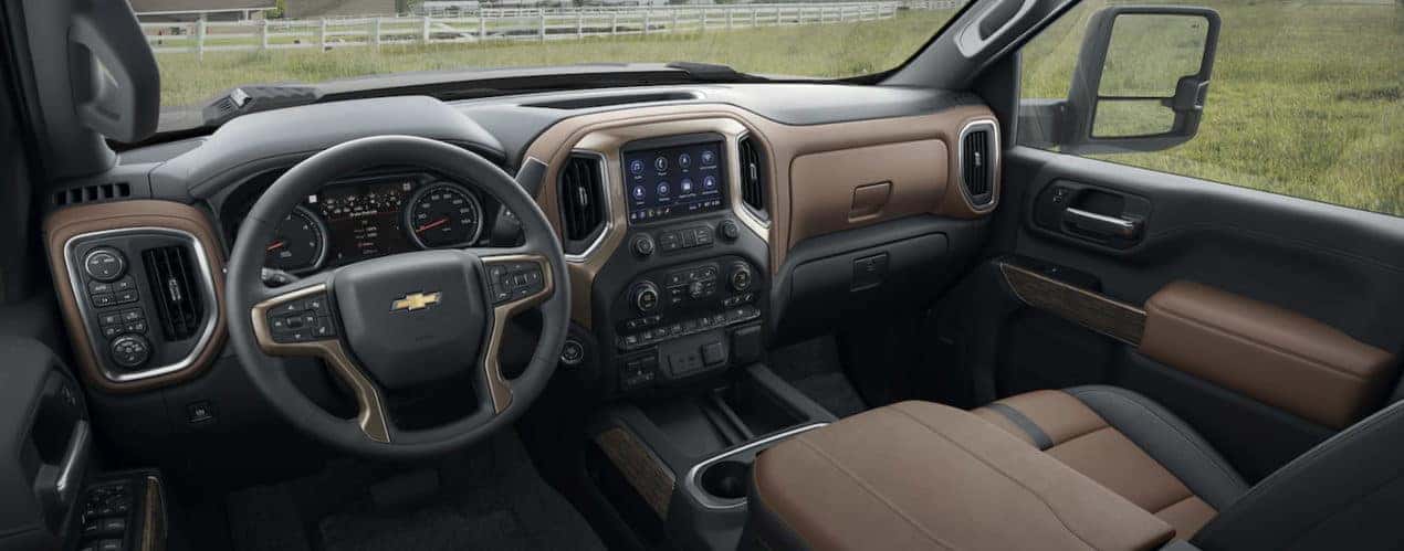 The black and brown interior of a 2023 Chevy Silverado 3500 HD shows the steering wheel and infotainment screen.