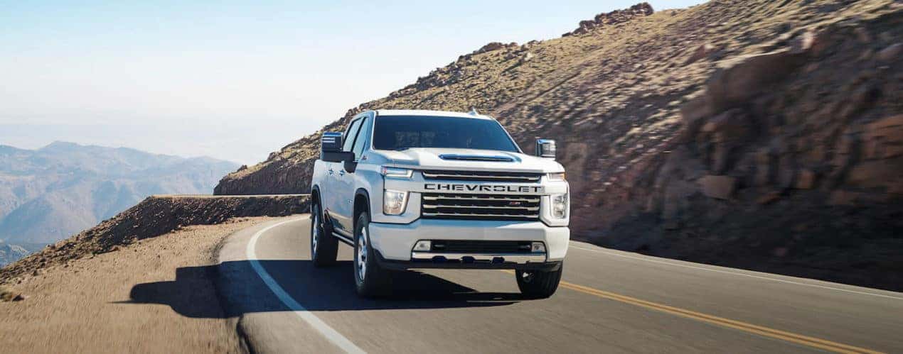 A white 2023 Chevy Silverado 3500 HD is shown driving on an open road.