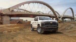 A white 2023 Chevy Colorado is shown from the front at an angle on a jobsite.