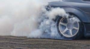 A car with performance tires is shown kicking up smoke.