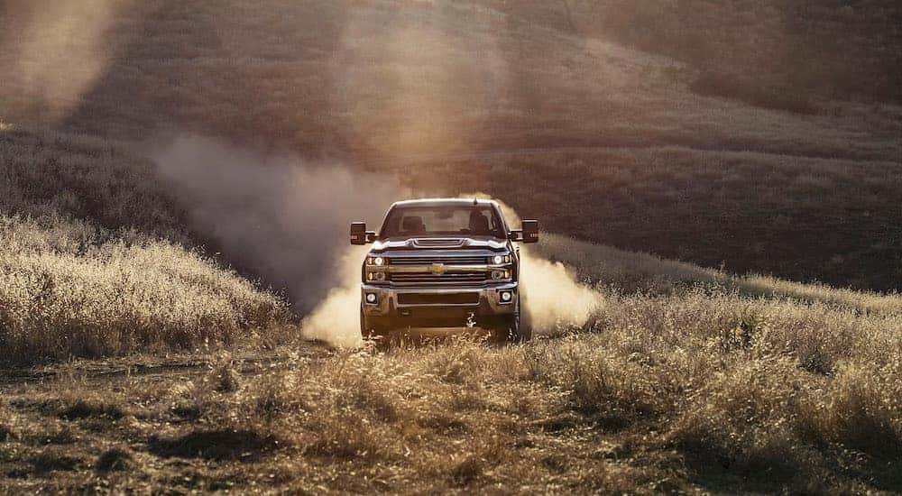 A black 2017 Chevy Silverado 2500HD is shown on a dusty trail after leaving a used Chevrolet dealer.