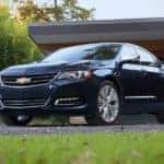 A dark blue 2018 Chevy Impala is shown in front of a garage.