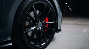 A close up shows a black rim and tire in a warehouse.