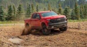 A red 2020 Chevy Silverado 1500 Z71 Trail Boss is shown from the front at an angle while off-road after leaving a dealer that has Chevy trucks for sale.