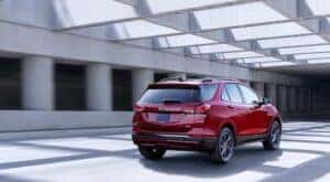 A red 2022 Chevy Equinox RS is shown from the rear at an angle after leaving a dealer that has used SUVs for sale.