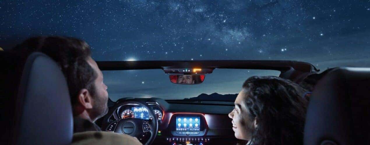 People are shown under a starry sky in a 2023 Chevy Camaro RS.
