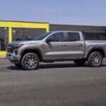 A silver 2023 Chevy Colorado Z71 is shown driving on a city street after looking for Chevy dealers in Indianapolis.
