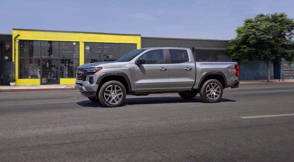 A silver 2023 Chevy Colorado Z71 is shown driving on a city street after looking for Chevy dealers in Indianapolis.