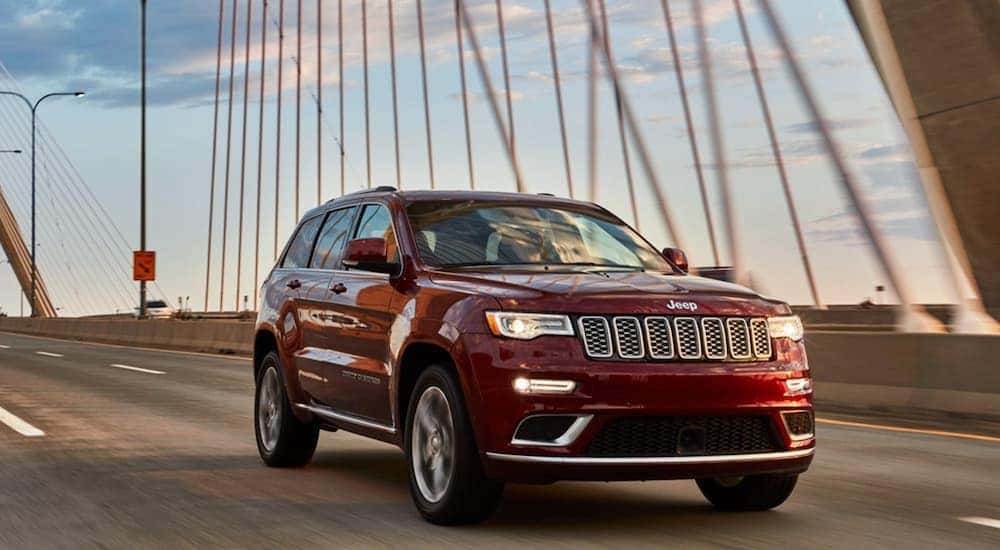 A red 2020 Jeep Grand Cherokee is shown driving on a bridge.