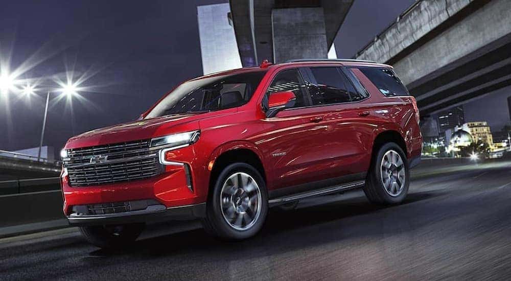 A red 2021 Chevy Tahoe is shown driving on a road after visiting McCluskey Chevrolet where they have used SUVs for sale.
