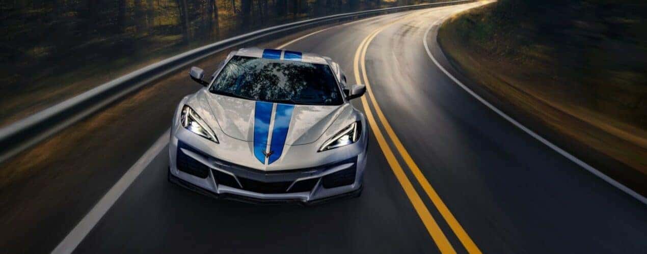 A silver 2024 Chevy Corvette E-Ray 3LZ is shown from the front driving on a wet road.