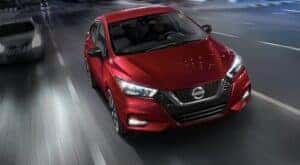 A red 2020 Nissan Versa is shown driving on a highway at night.