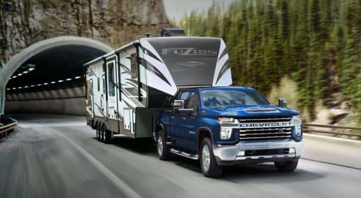 A blue 2021 Chevy Silverado 2500Hd Z71 is shown towing a trailer after viewing used trucks for sale in Cincinnati.