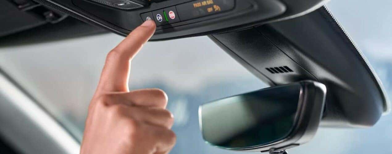 A person is shown pressing an OnStar button in a 2024 Chevy Blazer.
