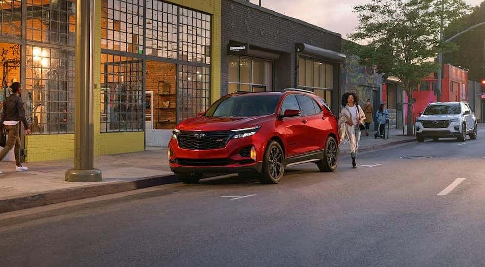 A red 2024 Chevy Equinox RS is shown parked near a store after a 2024 Chevy Equinox vs 2024 Nissan Rogue comparison.