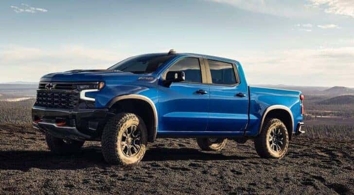 A blue 2024 Chevy Silverado 1500 ZR2 is shown angled left and parked off-road.