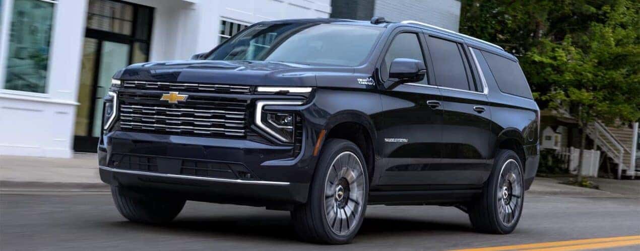 A black 2025 Chevy Suburban High Country driving in a city.