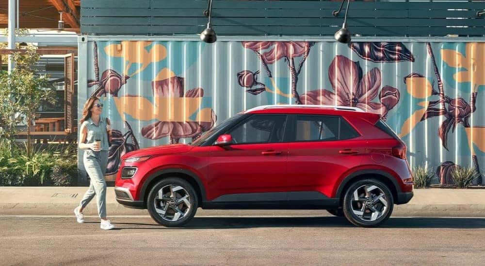 A side view of red 2023 Hyundai Venue Limited parked in a city.