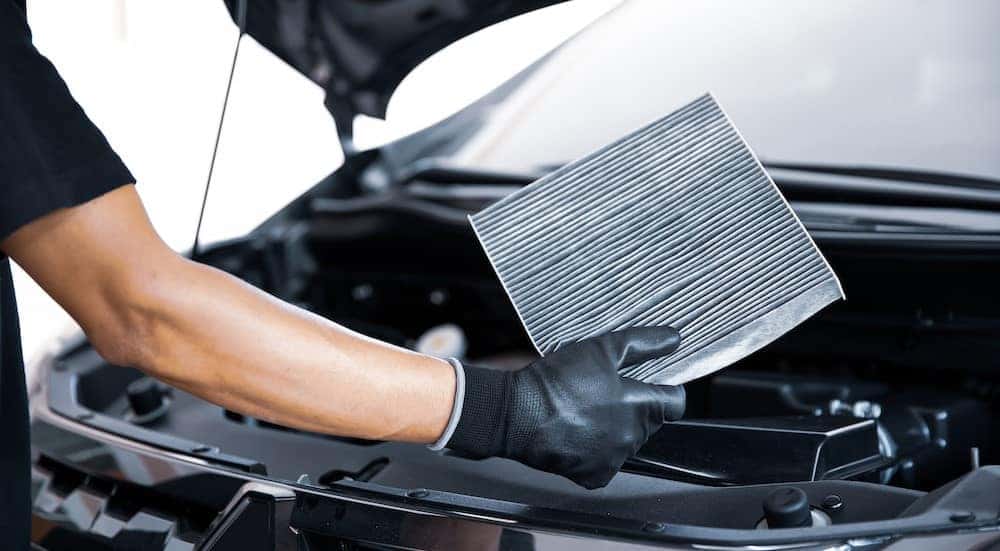 A mechanic is shown holding a used air filter.