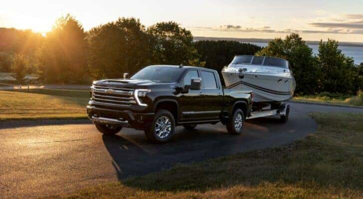 A black 2024 Chevy Silverado 2500 HD High Country towing a boat.