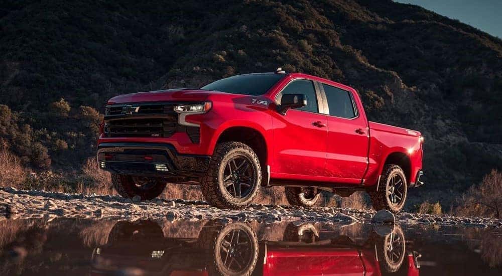 A red 2024 Chevy Silverado 1500 Z71 Trail Boss driving by a shallow lake.