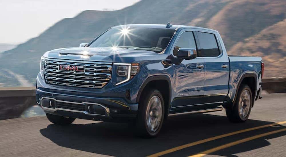 A blue 2024 GMC Sierra 1500 Denali is shown driving to visit a GMC service center.