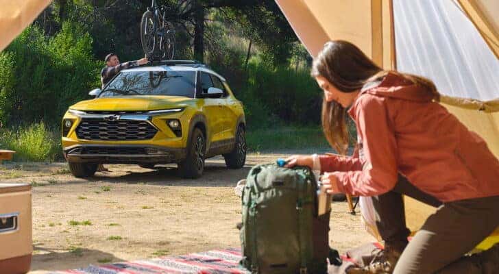 A yellow 2025 Chevy Trailblazer ACTIV parked at a campsite.