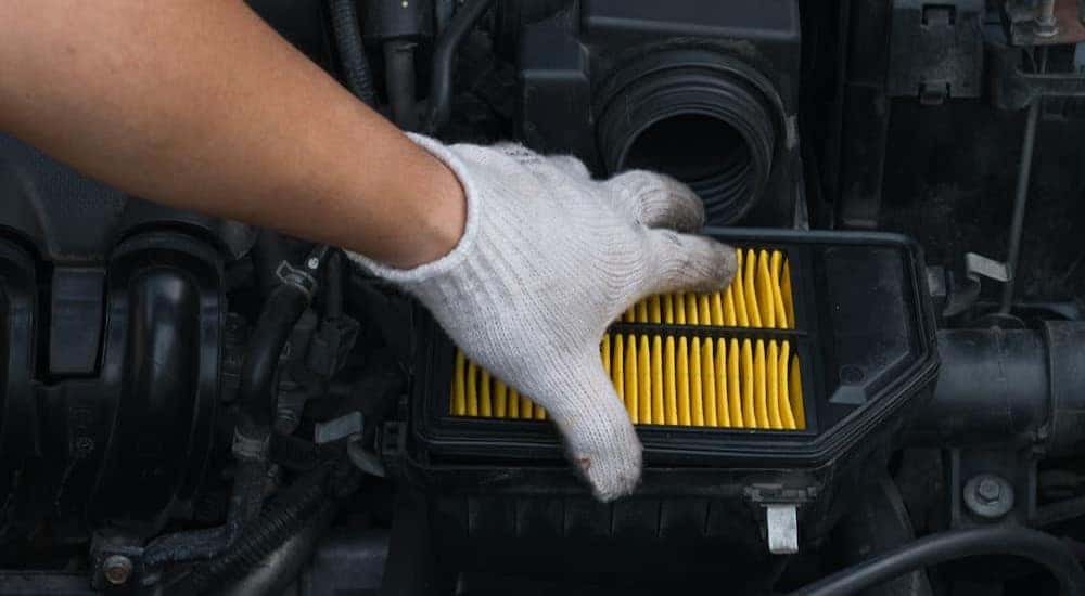 A mechanic is shown replacing an air filter.