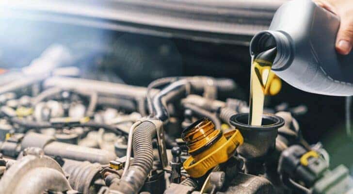 A can of oil being poured into an engine at a Ford service center.