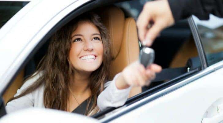 A person is shown handing car keys to another person at a Buick service center.