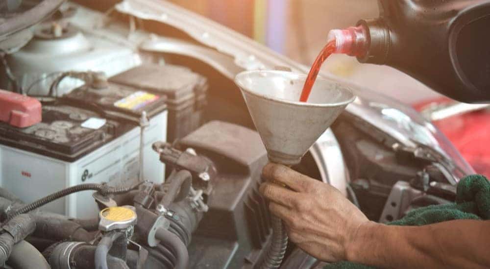 Transmission fluid is shown being poured into a funnel.