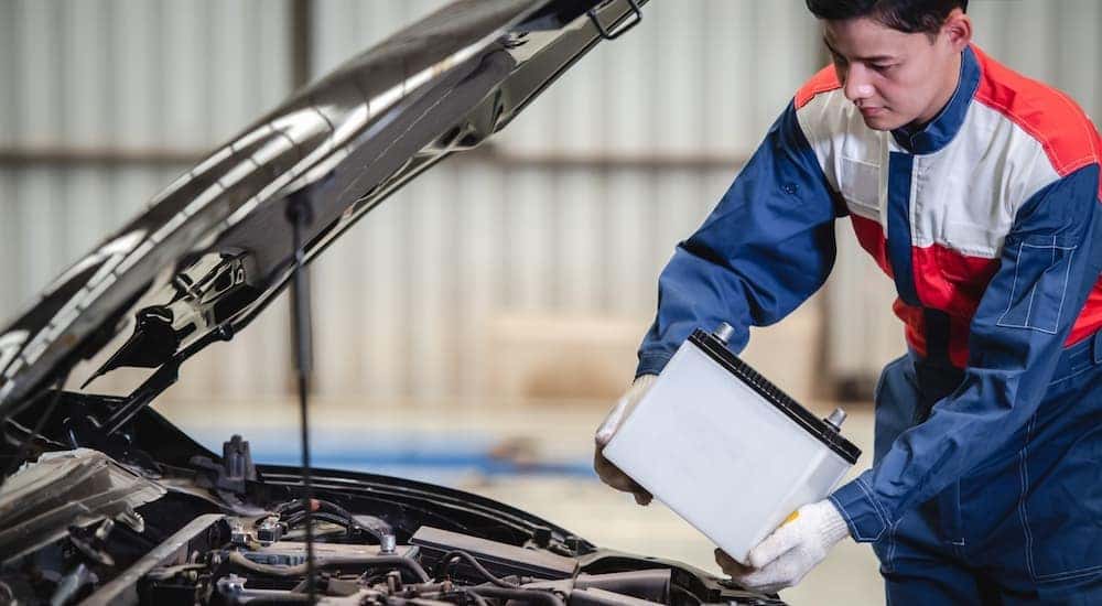 A mechanic is shown replacing a car battery.