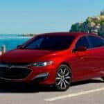 A red 2025 Chevy Malibu parked in front of the ocean.