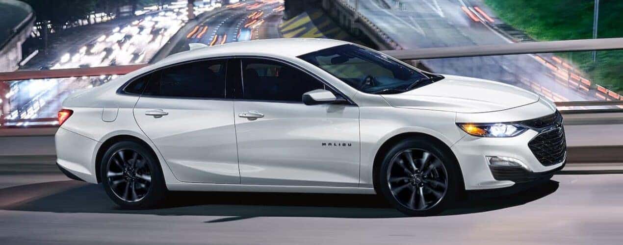 A white 2025 Chevy Malibu Sport Edition is shown driving on a bridge.