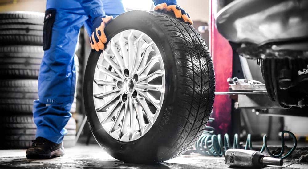 A mechanic rolling a tire through a Ford service center.