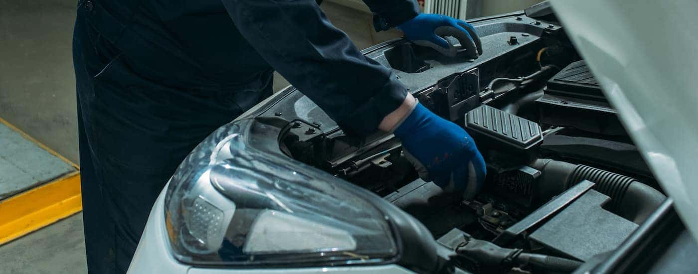 A mechanic replacing a car battery in a white car.
