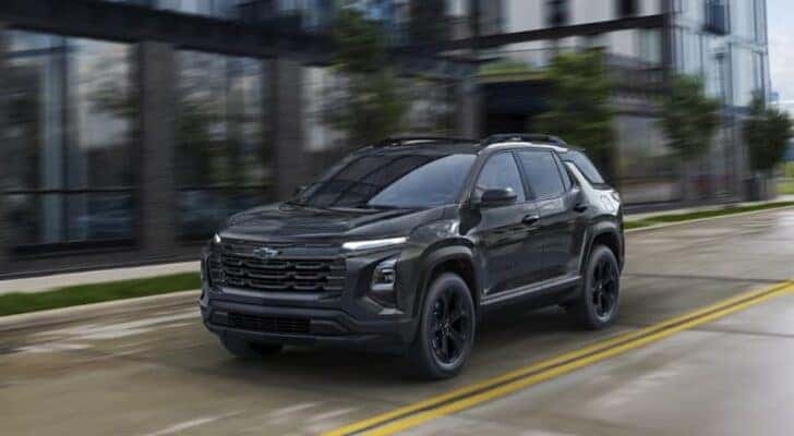 A black 2025 Chevy Equinox Midnight Edition is shown driving on a city street after viewing a Chevy Equinox for sale.