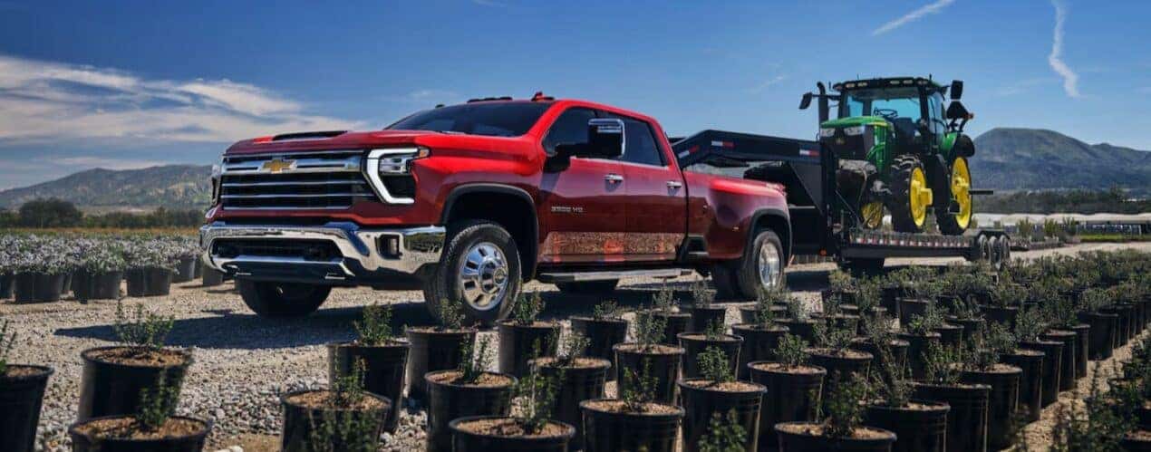 A red 2025 Chevy Silverado 3500 HD is shown towing a trailer.